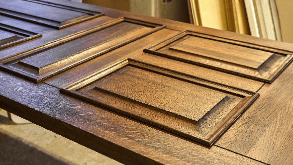 A finished oak raised-panel door laid flat on a workbench in a door shop.