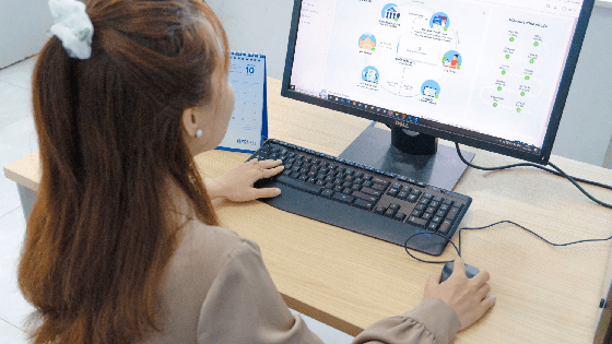 An office worker reviewing an ERP dashboard on a desktop monitor.