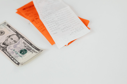 A dollar bill beside a pair of printed receipts.