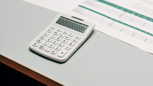 A calculator resting beside a printed spreadsheet on a desk.